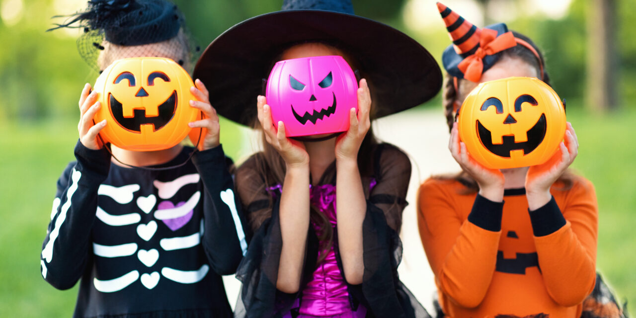 Happy Halloween! funny children in carnival costumes hide their heads behind buckets pumpkins outdoors halloween bark