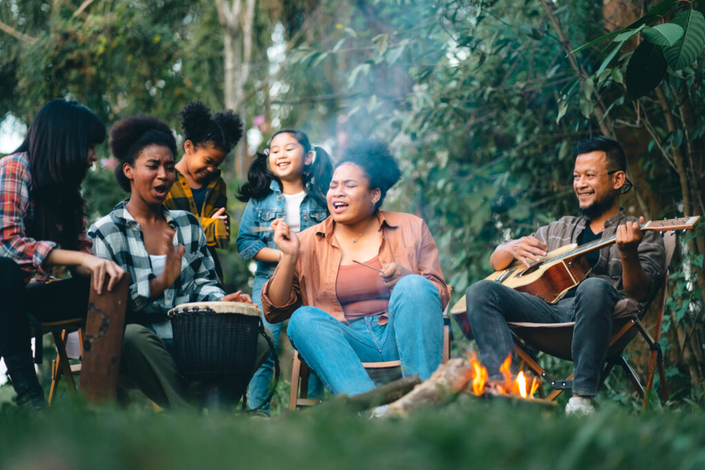 Family outside at fire singing with guitar